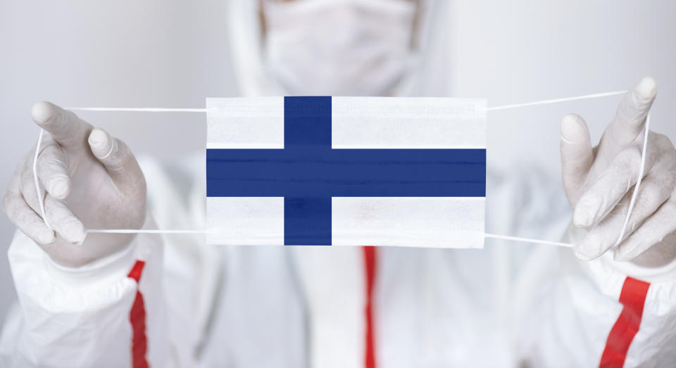 Healthcare personnel is holding Finnish Flag shaped surgical mask.