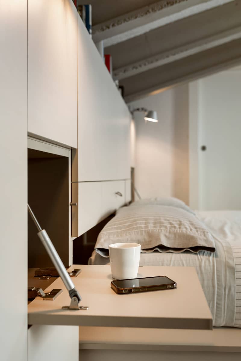 Mug and phone on shelf from modular wall unit in neutral toned room.
