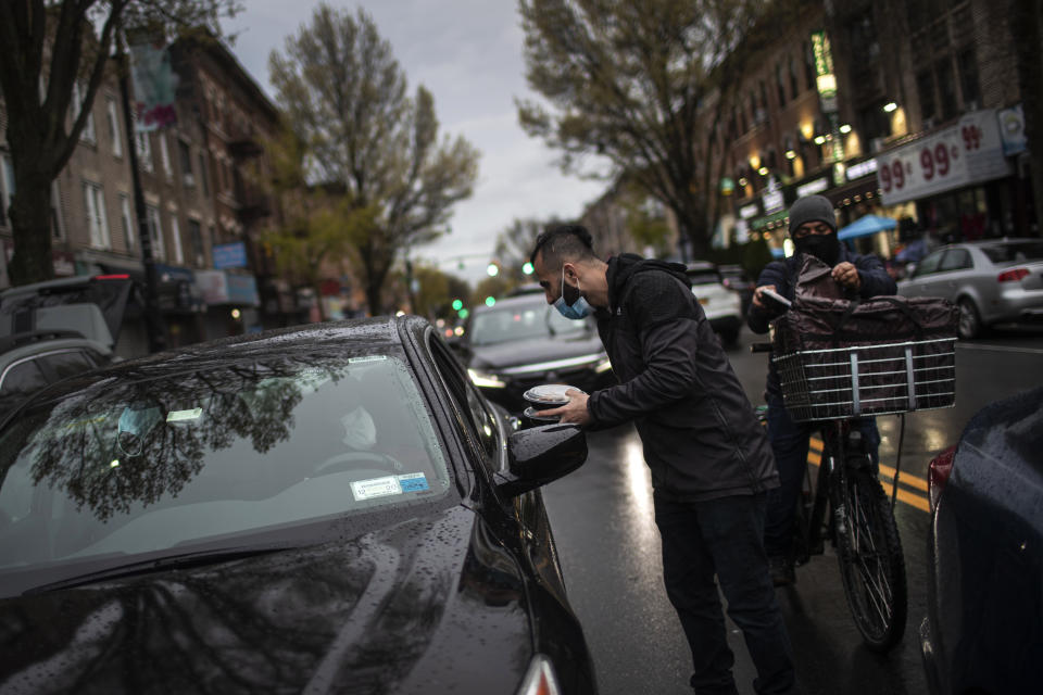 Soubhi Khalil, 25, a volunteer with Muslims Giving Back, hands out warm plates of food for "Iftar" where Muslims end their day of fasting during the month of Ramadan, in the Bay Ridge neighborhood of Brooklyn, New York, on Friday, April 24, 2020. (AP Photo/Wong Maye-E)