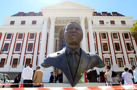 Members of the media are seen behind a bust of Nelson Mandela outside Parliament after it was announced that the State of the Nation address, due to be delivered by President Jacob Zuma, has been postponed, in Cape Town, South Africa, February 6, 2018. REUTERS/Sumaya Hisham