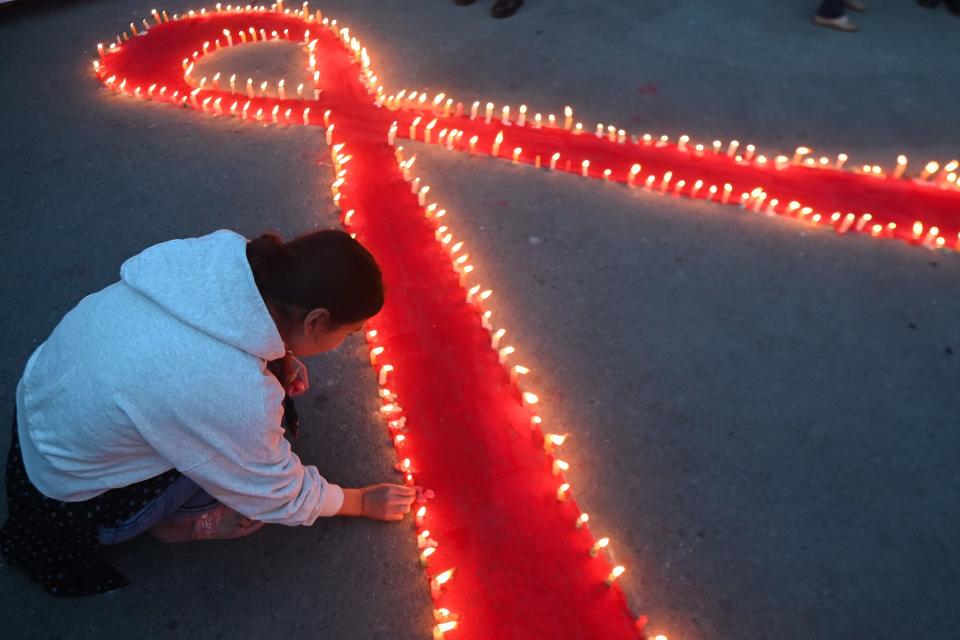 Volunteers' light candles arranged in a red ribbon shape on Nov. 30, 2023, on the eve of World AIDS Day in Kathmandu, Nepal.