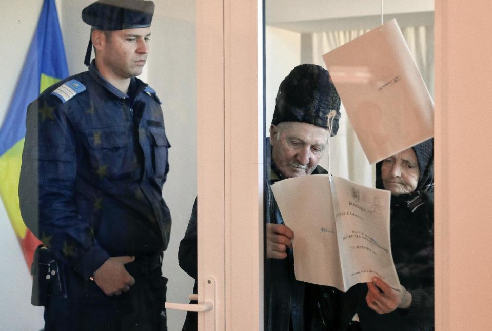An elderly couple examine sample voting bulletins before entering a voting station in Baleni Sarbi, Romania, Sunday, Dec. 11, 2016. Romanians are voting in a parliamentary election, a year after a massive anti-corruption drive forced the last Socialist prime minister from power in a country of about 19 million, one of the poorest in the European Union and perceived as one of the most corrupt. (AP Photo/Vadim Ghirda)