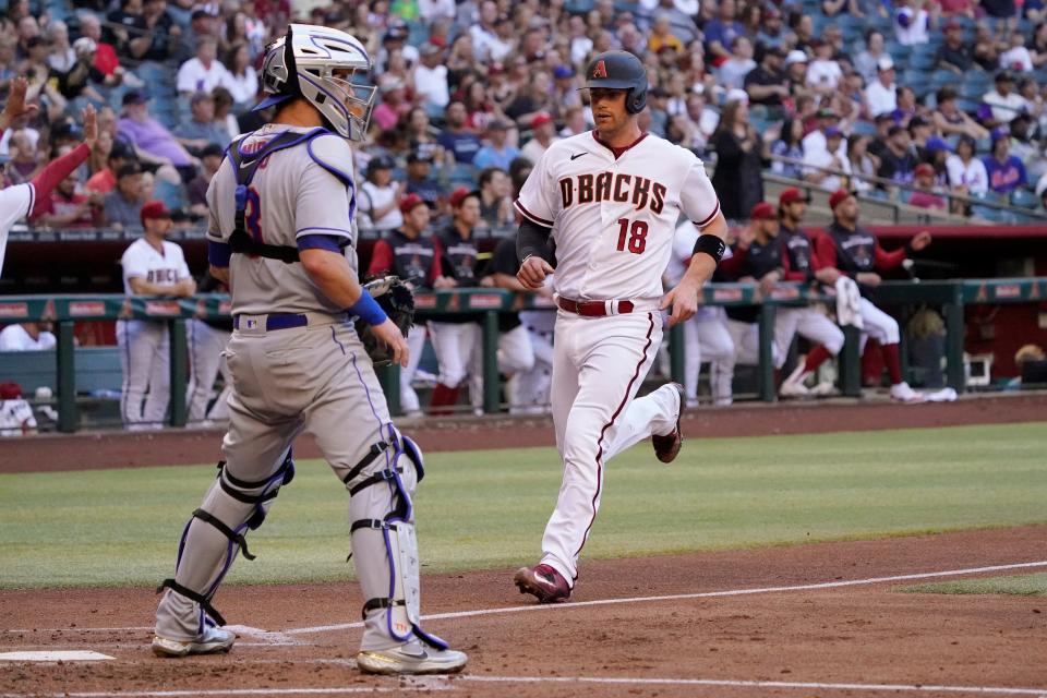 Arizona Diamondbacks' Carson Kelly (18) scores on a base hit by Daulton Varsho as New York Mets catcher Tomas Nido waits or the throw during the second inning of a baseball game, Saturday, April 23, 2022, in Phoenix.