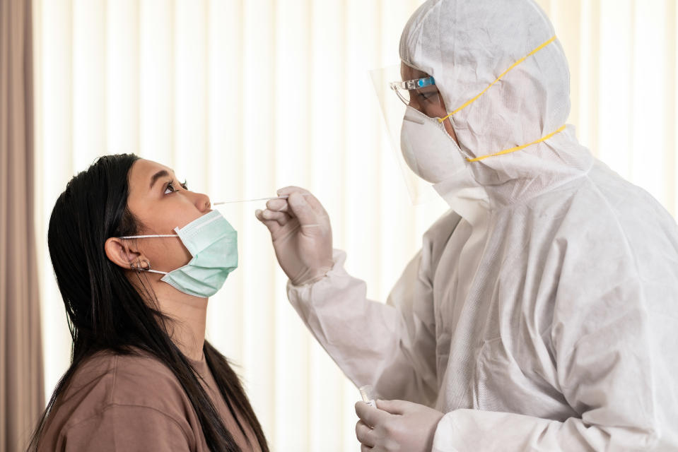 Medical staff with PPE suit test coronavirus covid-19 to asian woman by nose swab at hosputal. COVID-19 testing health care concept.