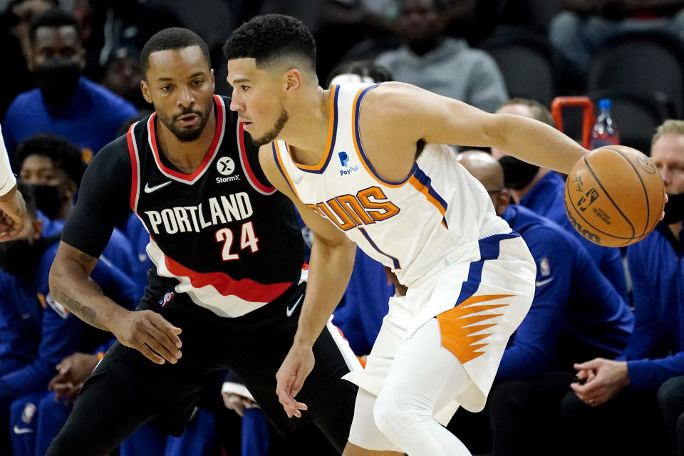 Phoenix Suns guard Devin Booker (1) looks to pass as Portland Portland Trail Blazers forward Norman Powell (24) defends during the first half of a preseason NBA basketball game, Wednesday, Oct. 13, 2021, in Phoenix. (AP Photo/Matt York)