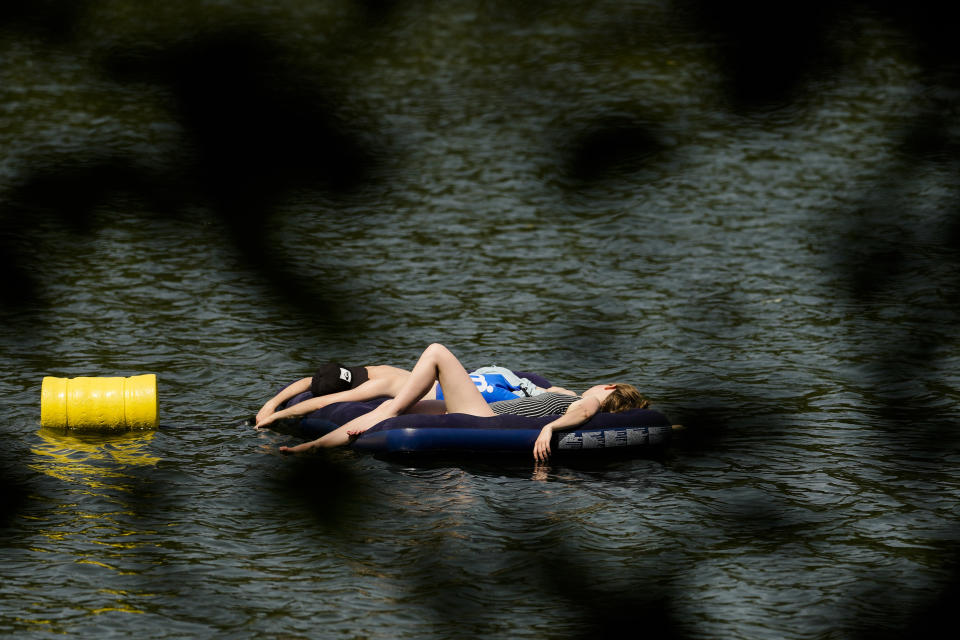 People rest on an air mattress on a hot summer day at the Orankesee lake in Berlin, Germany, Sunday, June 19, 2022. People flocked to parks and pools across Western Europe on Saturday for a bit of respite from an early heat wave. In Germany, where highs of 38 C (100.4 F) were expected, the health minister urged vulnerable groups to stay hydrated.(AP Photo/Markus Schreiber)