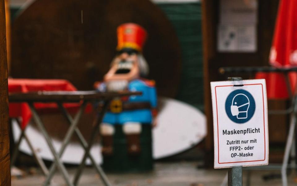 A face mask sign at a Christmas market in Cologne - Getty