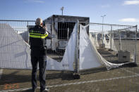 A police officer takes images of a torched coronavirus testing facility in the Dutch fishing village of Urk, Sunday, Jan. 24, 2021, after it was torch Saturday night by rioting youths protesting on the first night of a nation-wide curfew. (AP Photo/Peter Dejong)