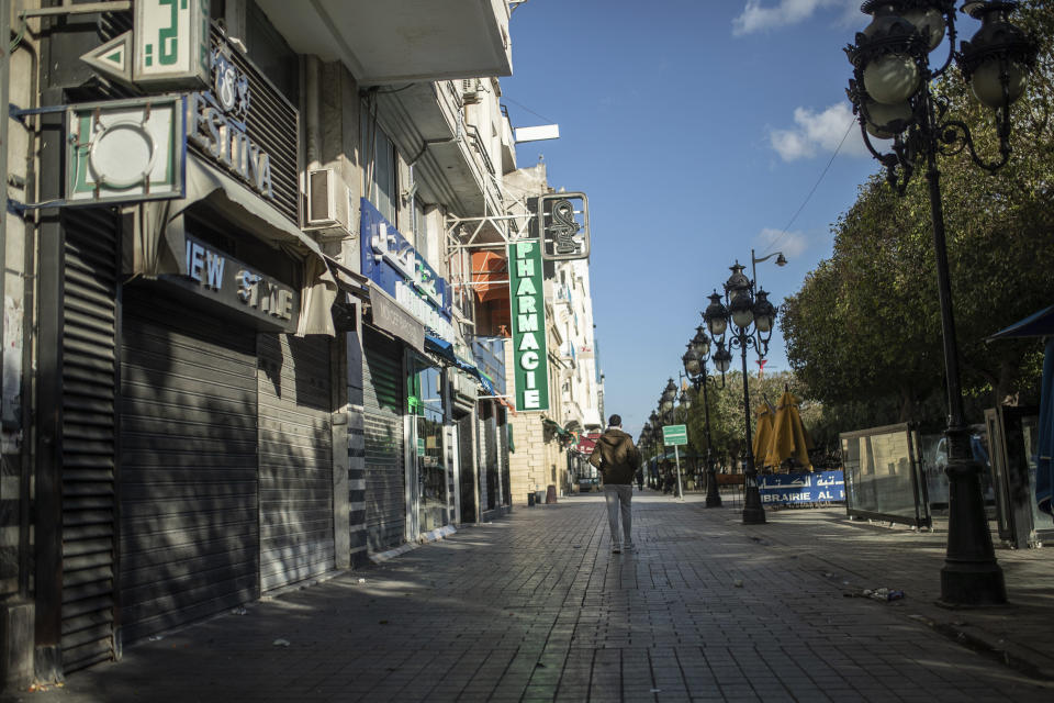 FILE - A man walks past closed shops in Tunis' landmark Avenue Habib Bourgiba, where massive protests took place in 2011, on the tenth anniversary of the uprising, during to a national lockdown after a surge in COVID -19 cases, in Tunis, Thursday, Jan. 14, 2021. Despite an election debacle, Tunisia's increasingly authoritarian president appears determined to upend the country's political system, threatening to unravel the fragile democracy and collapse the economy in the North African nation that a decade ago stood out as a model of good governance and economic prosperity in the aftermath of the Arab Spring protests. (AP Photo/Mosa'ab Elshamy, File)