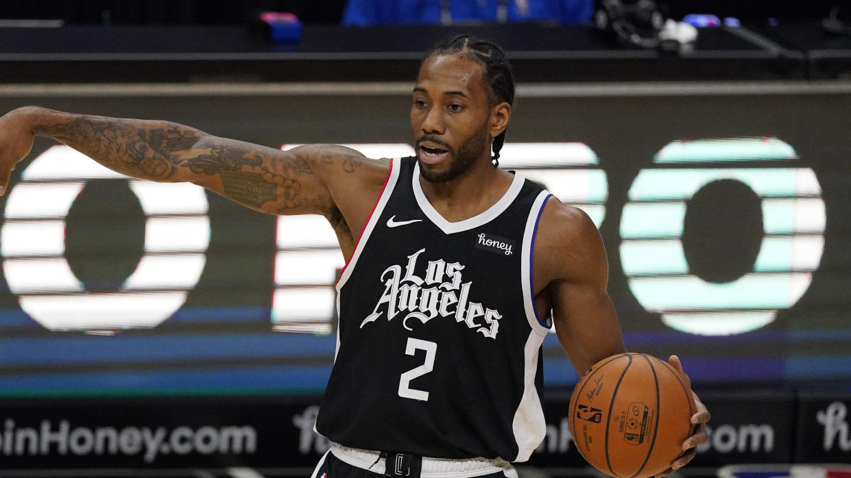 Kawhi Leonard points with one arm as he holds the ball with his other hand during a game.