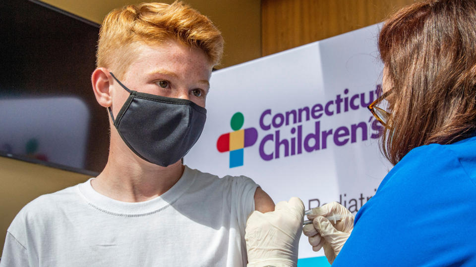 A 13-year-old boy wearing a mask is inoculated by a nurse in Hartford, Connecticut.