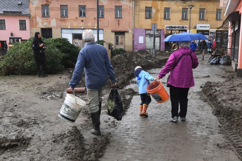 Local residents walk among rubble in a flooded street after heavy rainfall. Peøina Ludìk/CTK/dpa