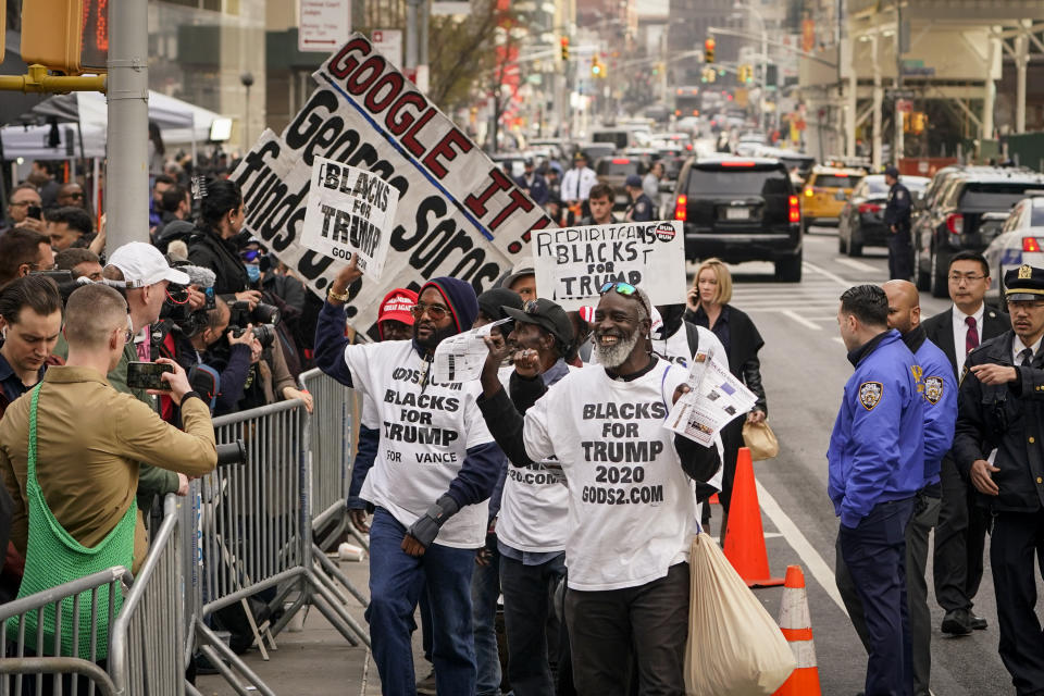 Simpatizantes del expresidente Donald Trump desfilan con sus carteles frente a los medios de comunicación y los curiosos reunidos frente al Tribunal Penal de Manhattan, el martes 4 de abril de 2023, en Nueva York. (AP Foto/John Minchillo)