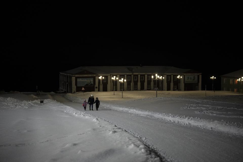 Personsa caminan durante una noche polar en Barentsburg, Noruega, el sábado 7 de enero de 2023. (AP Foto/Daniel Cole)