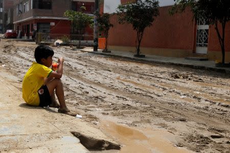 A child sits on a street pavement after a landslide and a flood occurred in San Juan de Lurigancho distritct, in Lima, Peru February 1, 2017. REUTERS/Guadalupe Pardo