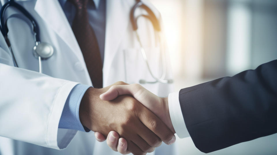 A doctor in scrubs shaking hands with a patient, representing the healthcare services provided to individuals and families.