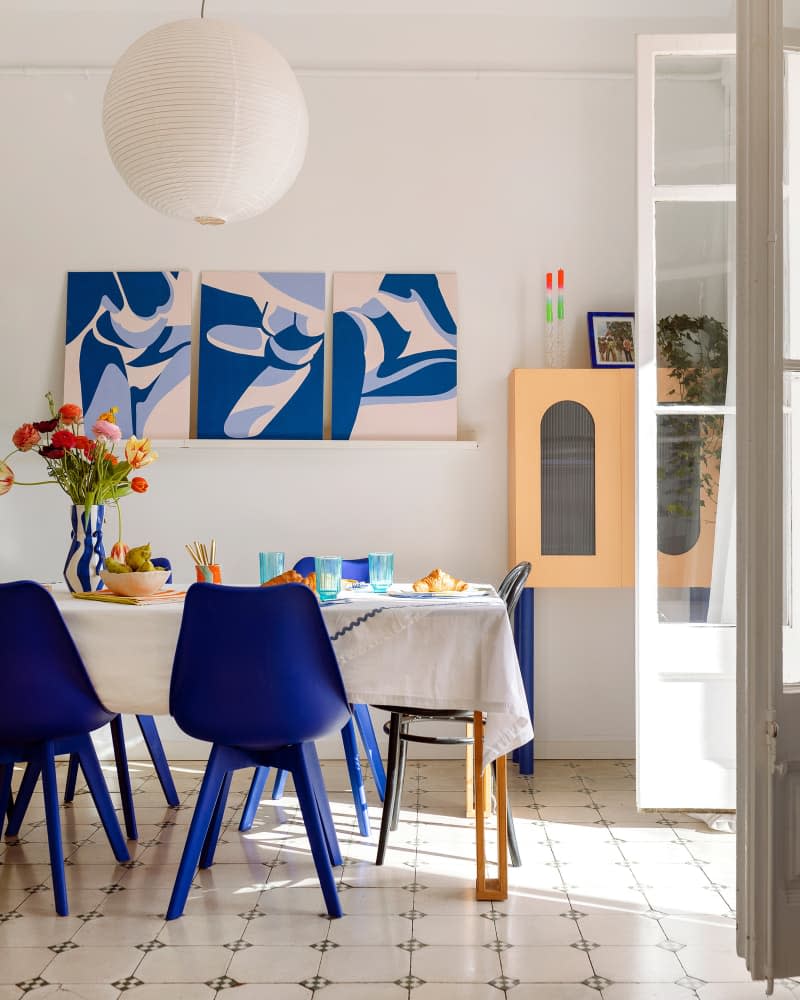 Dining area with blue chairs and artwork on the wall.