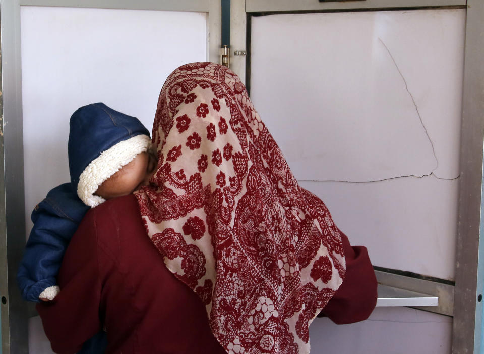 A voter carries her son as she prepares to cast her ballot on constitutional amendments during the second day of three-day voting at polling station in Cairo, Egypt, Sunday, April 21, 2019. Egyptians are voting on constitutional amendments that would allow President Abdel-Fattah el-Sissi to stay in power until 2030.(AP Photo/Amr Nabil)