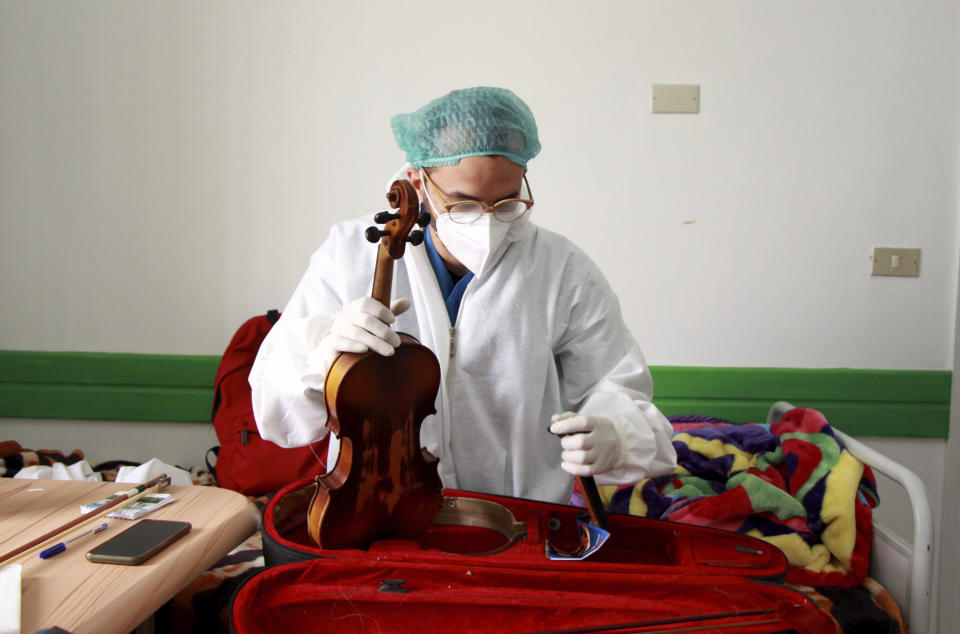 Dr. Mohamed Salah Siala takes out his violin to play for patients on the COVID wards of the Hedi Chaker hospital in Sfax, eastern Tunisia, Saturday Feb. 20, 2021. When the 25-year-old decided to get out his violin one day at Hedi Chaker Hospital in city of Sfax and play, it won praise for boosting the morale of virus sufferers who remained isolated and needed a smile. (AP Photo)