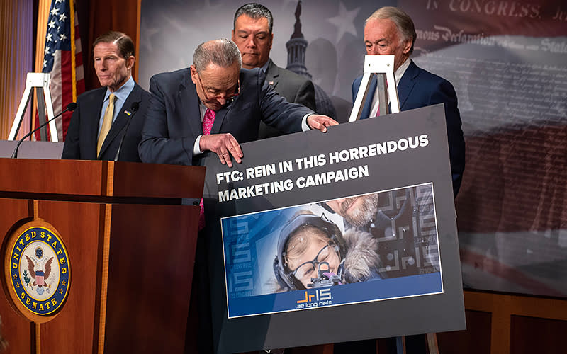 Senate Majority Leader Charles Schumer (D-N.Y.) adjusts a sign at a press conference to discuss WEE1 Tactical’s marketing of a “JR-15” rifle toward children on Jan. 26. <em>Annabelle Gordon</em>