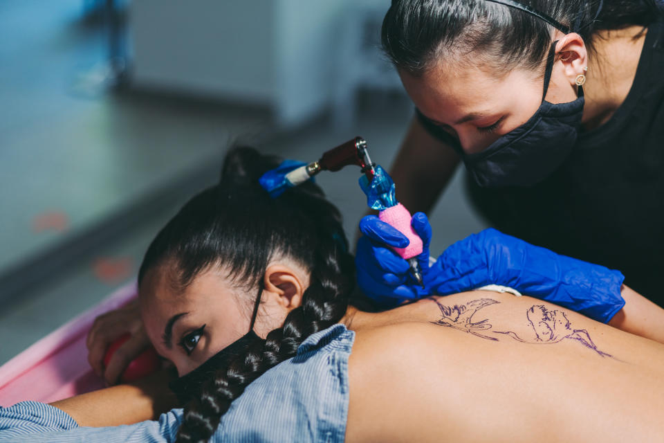 Tattoo artist working on a client's back piece