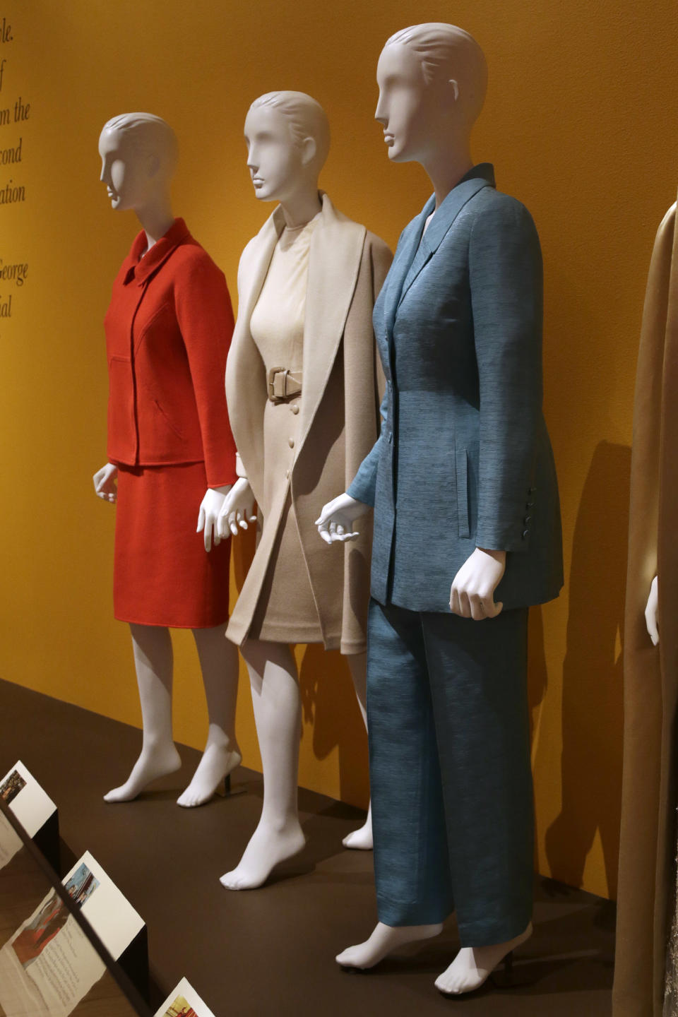 An Oscar de la Renta pantsuit worn by former first lady Hillary Rodham Clinton, right, is displayed next to de la Renta dresses worn by Nancy Regan, center, and Laura Bush at the Clinton Presidential Library in Little Rock, Ark., Monday, July 8, 2013. The "Oscar de la Renta: American Icon" exhibit is on display at the Clinton library until Dec. 1. (AP Photo/Danny Johnston)