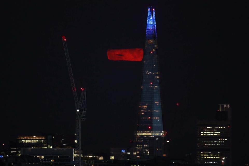 A full Moon, known as the Sturgeon Moon, is partially seen from behind clouds over the Shard building in London (PA)