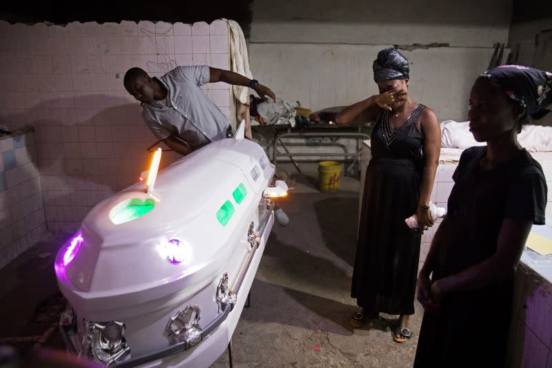 Foto de archivo de dos personas construyendo un ataúd con forma de aviónn en Saint-Marc, Haiti