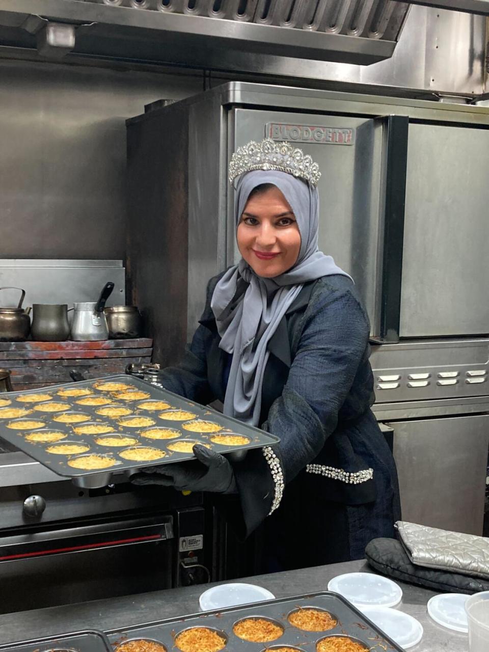 A woman holds a tray of baked goods.