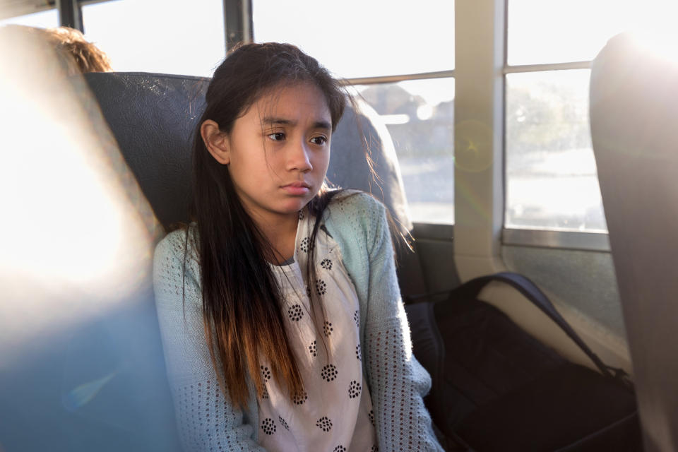 A little girl looking sad on the school bus