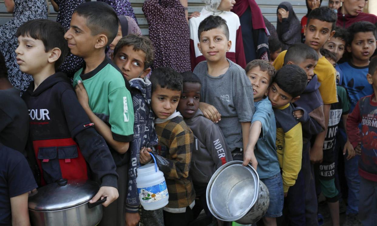 <span>Palestinian children line up for food distributed by charity organisations in Deir al-Balah, Gaza, on 5 April.</span><span>Photograph: Anadolu/Getty Images</span>