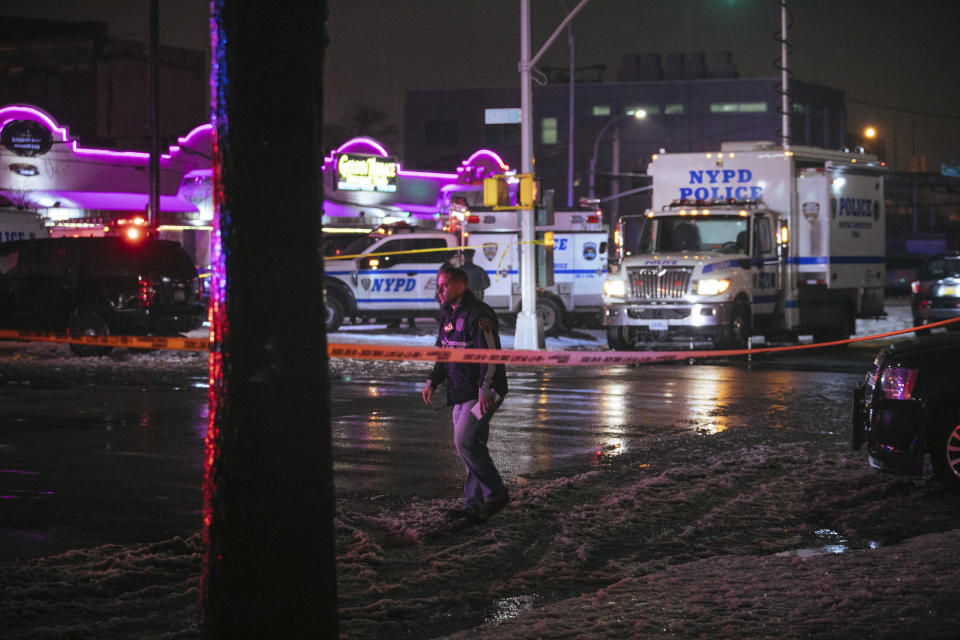 Investigators look over the area after a few New York City police officers were shot while responding to a robbery at a T-Mobile store in the Queens borough of New York on Tuesday, Feb. 12, 2019. (AP Photo/Kevin Hagen)