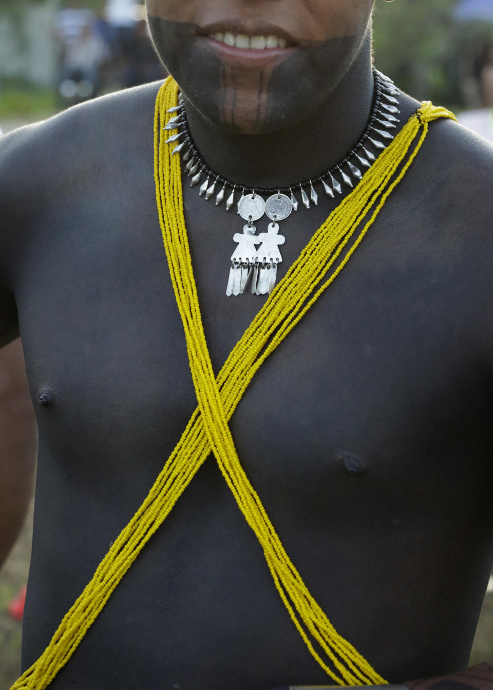 In this Nov. 25, 2018 photo, an Embera indigenous man poses for a photo during during the second edition of the Panamanian indigenous games in Piriati, Panama. He stained his arms and face with black ink extracted from a mountainous fruit. (AP Photo/Arnulfo Franco)