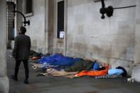 A man walks past homeless people sleeping under the portico of St. Paul's Church in Covent Garden, London, Tuesday, Dec. 10, 2019. Britain goes to the polls on Thursday, Dec. 12. (AP Photo/Thanassis Stavrakis)