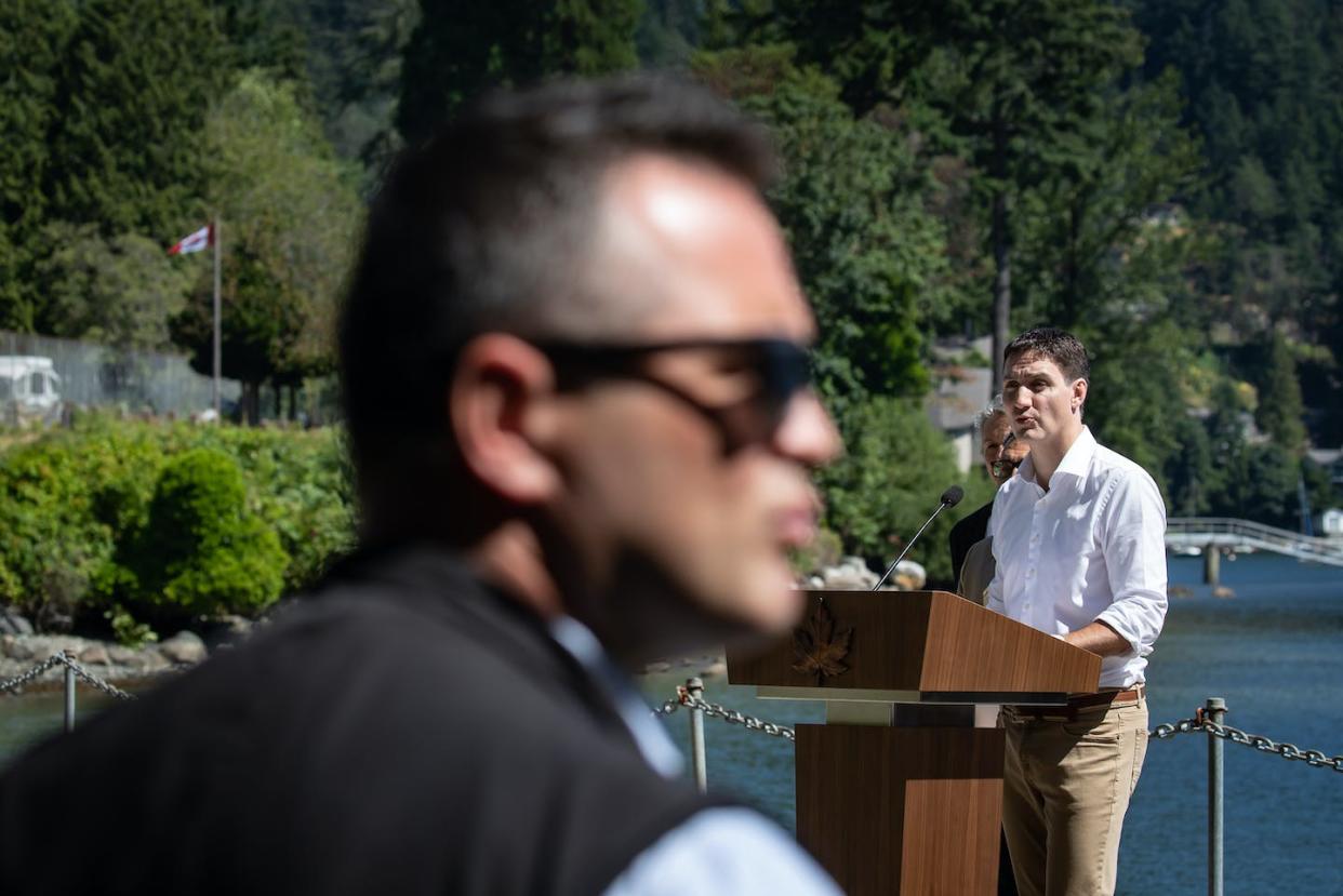Prime Minister Justin Trudeau speaks during a news conference as a member of his RCMP security detail stands by on Bowen Island, B.C., in July 2022. THE CANADIAN PRESS/Darryl Dyck