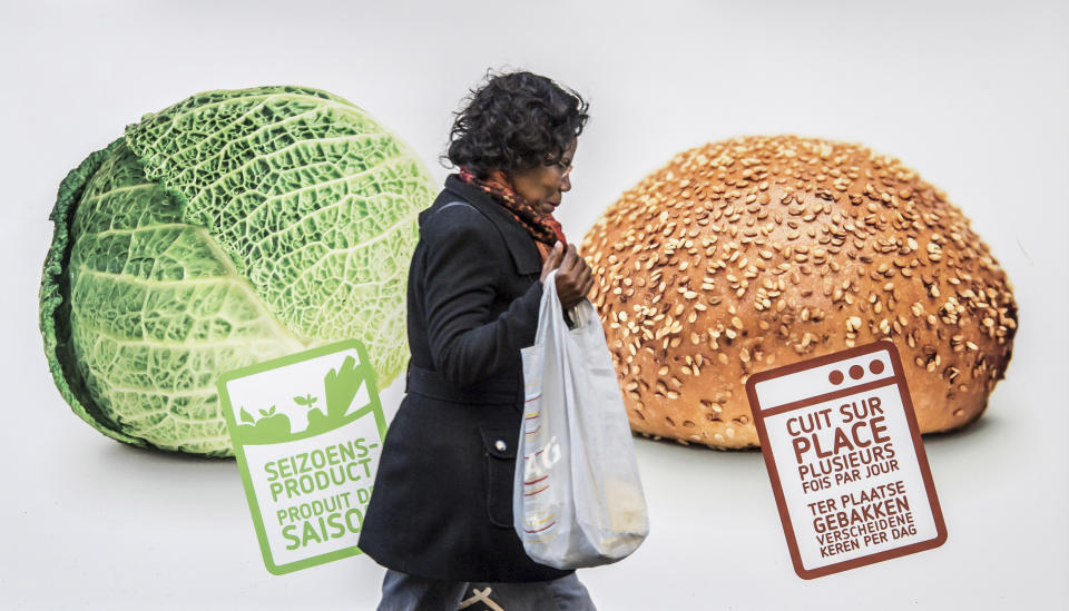 A woman walks by an advertisement for vegetables and bread in Brussels on Thursday, Nov. 22, 2012. As leaders from the 27-nation European Union gather in Brussels to debate the organization’s budgets for the years 2014-2020, they’ll talk not only about economic growth but crop growth, as well. Fully 41 percent of the EU’s budget goes to agriculture. Signs read from left to right, 'Seasonal Products' and 'freshly baked several times a day'. (AP Photo/Geert Vanden Wijngaert)