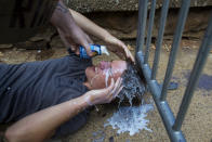 <p>Dieser Gegendemonstrant kriegt von einem Mitstreiter Milch in die Augen, nachdem er mit Pfefferspray in Berührung kam. (Bild: AP Photo) </p>