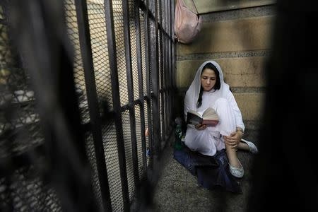 Aya Hijazi, founder of a non-governmental organisation that looks after street children, sits reading a book inside a holding cell as she faces trial on charges of human trafficking, sexual exploitation of minors, and using children in protests, at a courthouse in Cairo, Egypt March 23, 2017. REUTERS/Mohamed Abd El Ghany