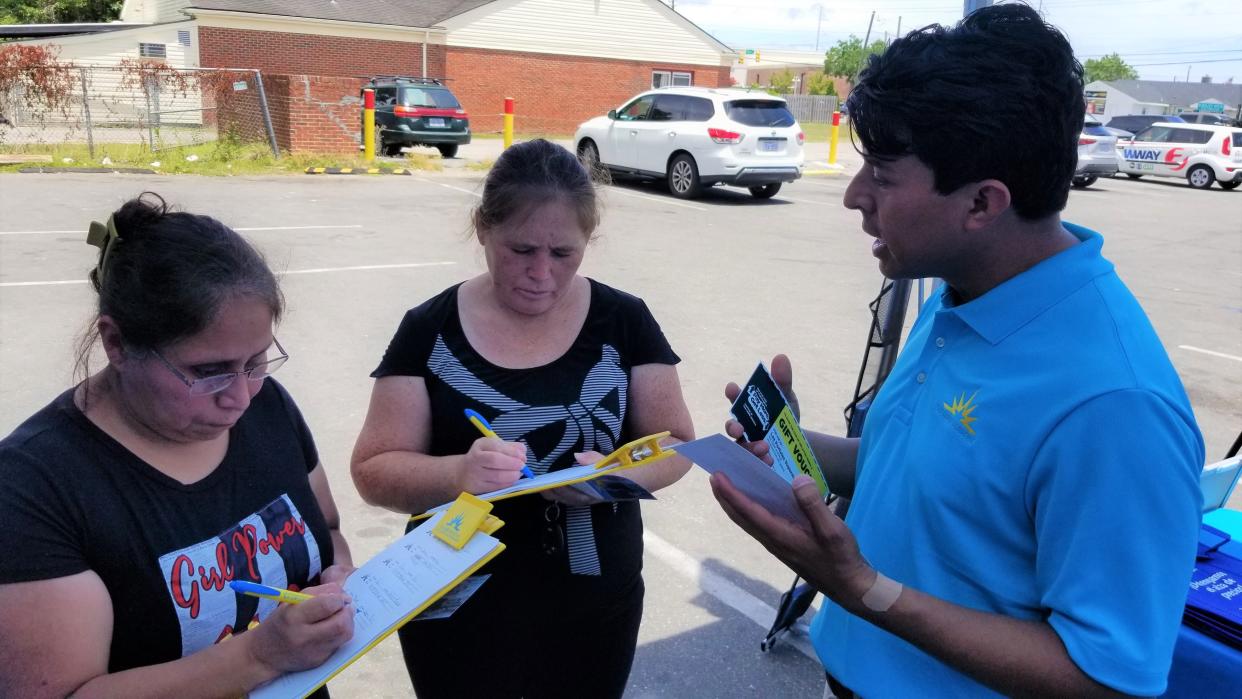 Jeffrey Baldwin,  grassroots engagement director, right, passes out grocery gift certificates to customers at Los Portales Supermarket.