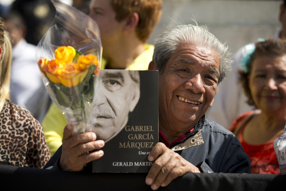 A well-wisher holds flowers and an autobiography of Colombian Nobel Literature laureate Gabriel Garcia Marquez, as he waits outside the Palace of Fine Arts to pay his respect to the beloved author, in Mexico City, Monday, April 21, 2014. Garcia Marquez died Thursday April 17, 2014 at his home in Mexico City. The author's magical realist novels and short stories exposed tens of millions of readers to Latin America's passion, superstition, violence and inequality. (AP Photo/Rebecca Blackwell)