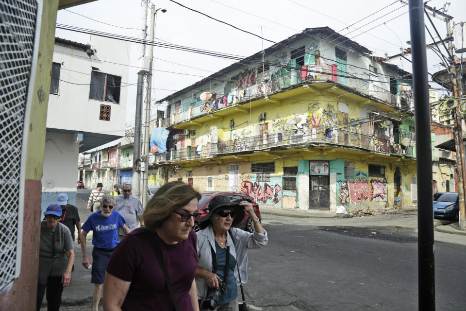 In this Dec. 4, 2019 photo, tourists walk through the El Chorrillo neighborhood where former Gen. Manuel A. Noriega operated his headquarters and is an area that was bombed during the 1989 U.S. invasion, in Panama City. U.S. troops were tasked by then-President George H.W. Bush with capturing Noriega, protecting the lives of Americans living in Panama and restoring democracy to the country that a decade later would take over control of the Panama Canal. (AP Photo/Arnulfo Franco)