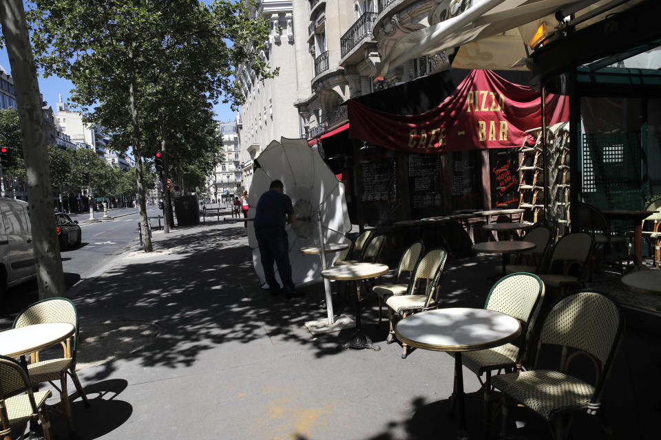 A man prepares the terrace of a restaurant in Paris, Monday, June 1, 2020, as France gradually lifts its Covid-19 lockdown. France is reopening tomorow its restaurants, bars and cafes as the country eases most restrictions amid the coronavirus crisis. (AP Photo/Christophe Ena)