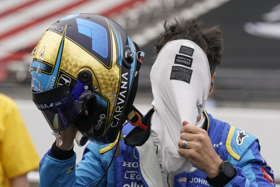 Jimmie Johnson pulls off his balaclava during qualifications for the Indianapolis 500 auto race at Indianapolis Motor Speedway, Saturday, May 21, 2022, in Indianapolis. (AP Photo/Darron Cummings)