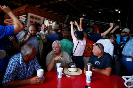 People sit at a table as Democratic 2020 U.S. presidential candidate and former U.S. Vice President Joe Biden greets people at the Iowa State Fair in Des Moines