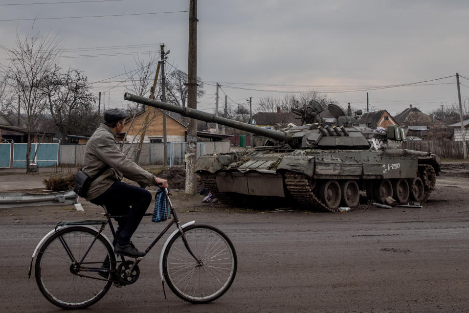 A man rides his bike past a destroyed Russian tank in Trostyanets, Ukraine. European stocks fell as the World Bank downgraded its 2022 global economic forecast due to the ongoing conflict in Ukraine. Photo: Chris McGrath/Getty Images