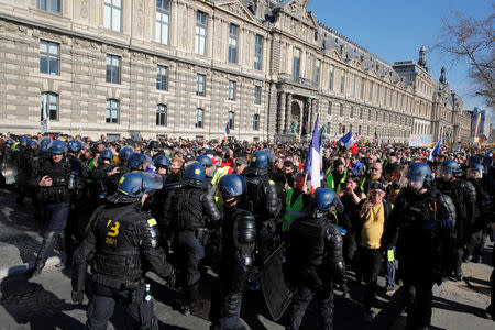 French gendarmes walk ahead of protesters wearing yellow vests as they attend a demonstration by the "yellow vests" movement in Paris, France, February 23, 2019. REUTERS/Philippe Wojazer