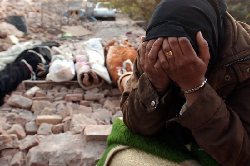 A woman mourns December 27, 2003, one day after an earthquake, as bodies await burial in Bam, a city about 630 miles southeast of Tehran, Iran. File Photo by Ali Khaligh/UPI