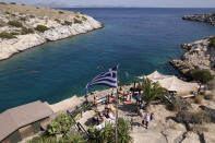 People are pictured next to a beach bar at Vouliagmeni suburb, southwest of Athens, on Thursday, July 29, 2021. One of the most severe heat waves recorded since 1980s scorched southeast Europe on Thursday, sending residents flocking to the coast, public fountains and air-conditioned locations to find some relief, with temperatures rose above 40 C (104 F) in parts of Greece and across much of the region. (AP Photo/Yorgos Karahalis)