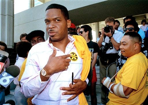 Luther Campbell, leader of hip hop group of 2 Live Crew and president of its record label, points to the warning sticker on his shirt, identical to the one on the group's controversial album "Nasty As They Wanna Be" outside federal court in Fort Lauderdale, Fla., March 16, 1990. The group filed a suit trying to stop obscenity arrests for the sales of their album.  (AP Photo/Beth Keiser)