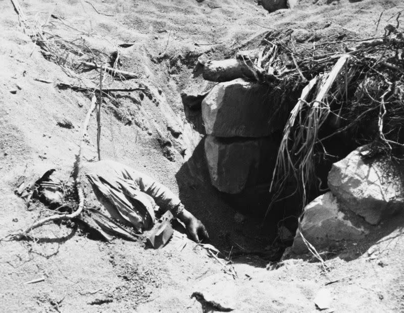 A dead Japanese soldier partially covered by sand at the entrance to a pillbox on Iwo Jima